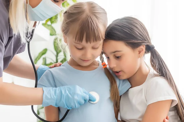 Junge Ärztin mit kleiner Patientin fühlt sich schlecht ärztliche Untersuchung mit Stethoskop. — Stockfoto