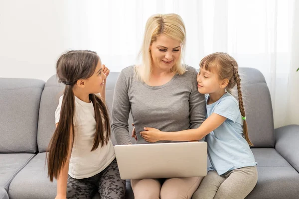 Sorridente madre con i bambini che utilizzano il computer portatile a casa — Foto Stock