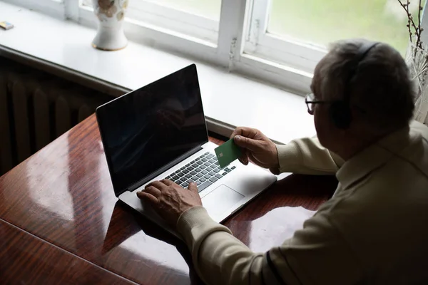 Літній чоловік в окулярах використовує ноутбук вдома — стокове фото