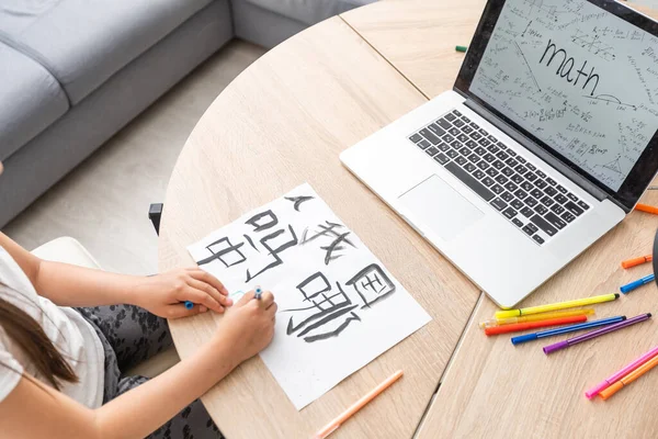 little girl learning chinese while using her laptop computer in the living room at home. family activity concept.