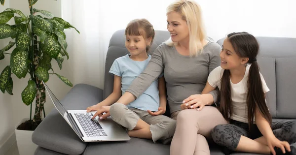 Leende mamma med små barn som använder laptop hemma — Stockfoto