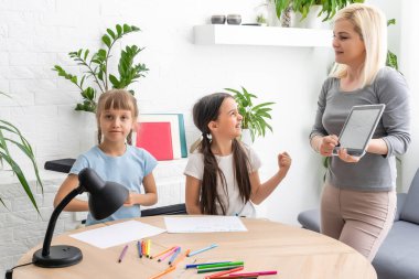 Güzel genç anne, kızlarına ödevlerinde yardım ediyor..
