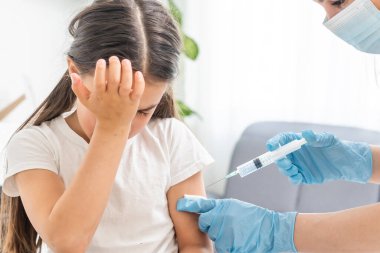 Küçük kız muayenehanedeki çocuk doktorundan aşı oluyor.