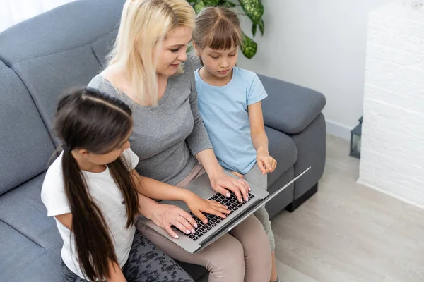 A trabalhar em casa com um miúdo. Mãe feliz e filha compras on-line, usando laptop juntos. Mulher abraçando criança. Local de trabalho freelancer na mesa da cozinha. Negócios femininos, comunicação virtual. — Fotografia de Stock