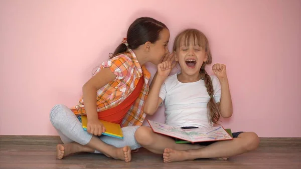 Belle bambine stanno leggendo un libro. Il concetto di istruzione. Isolato su sfondo rosa — Foto Stock