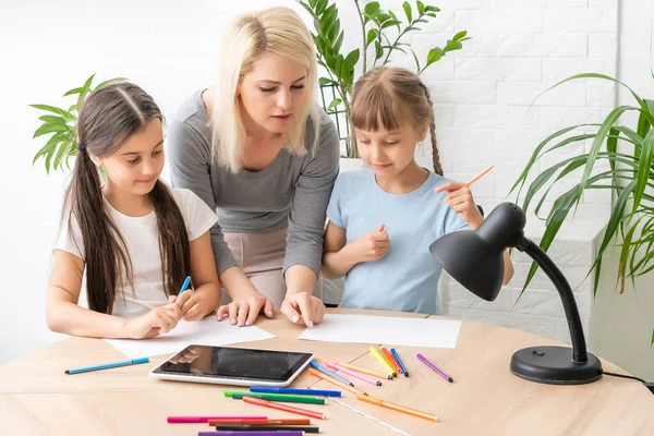 Madre e due figlie che fanno i compiti di scrittura e lettura a casa — Foto Stock