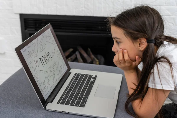 Menina entediada com laptop em casa. Criança gira a fazer trabalhos de casa no computador. Educação online moderna, conceito de comunicação e tecnologia, espaço de cópia. — Fotografia de Stock