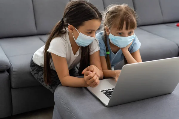 Jeunes filles de l'école primaire avec masque de protection du visage regarder classe d'éducation en ligne. Coronavirus ou Covid-19 concept de verrouillage de l'éducation. — Photo