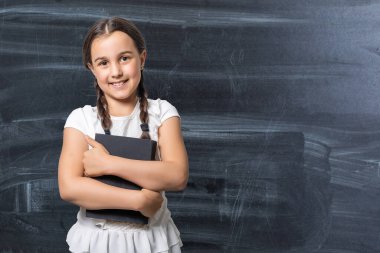 Esmer küçük kız, beyaz arka planda izole edilmiş bir kitap okuyor.