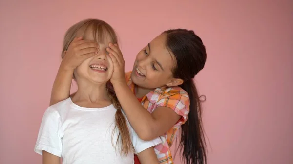 Due ragazze felici che si abbracciano isolate su sfondo rosa — Foto Stock