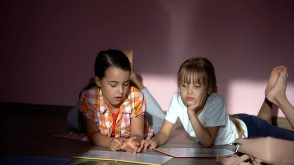 Concept de famille, de loisirs et d'enfance - sœurs heureuses allongées sur le sol et faisant leurs devoirs à la maison — Photo