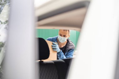 Kargo şoförü koltukta paketler ile araba kullanıyor.