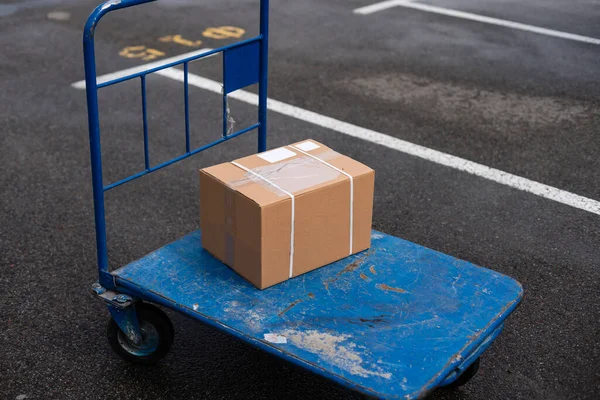 Brown cardboard moving box in the cart — Stock Photo, Image