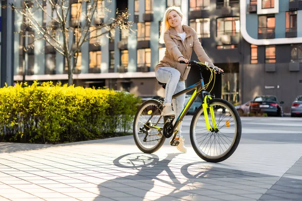 阳光明媚的日子，一位可爱的年轻女子骑着自行车在城市的大街上摆姿势 — 图库照片
