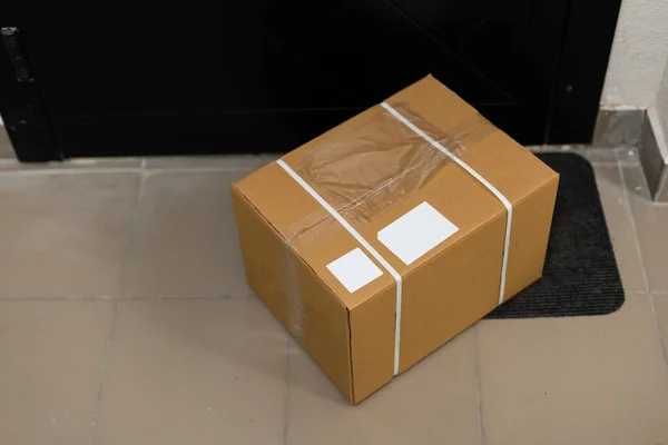 Картонна коробка на килимку біля вхідних дверей — стокове фото