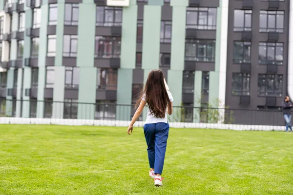 Bambina che cammina sul prato verde nel parco — Foto Stock