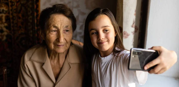 Bisabuela muy vieja y nieta con un teléfono inteligente en línea —  Fotos de Stock