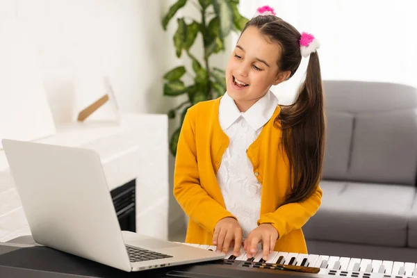 Homeschool little young kid girl learning piano from computer connecting to internet music online class by school teacher. New normal lifestyle and education, student study at home concept. — Stock Photo, Image