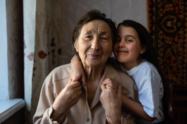 Küçük bir kız bebek ve çok yaşlı bir kadın. Küçük çocuk büyükannesine sarılıyor. Torunum.