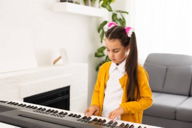 Güzel kız elektronik bir piyano çalarken şarkı söylüyor.