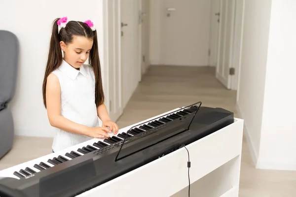 조명 실에서 피아노를 치고 있는 아름다운 소녀 — 스톡 사진