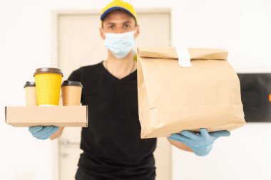 Karton kutuları tıbbi lastik eldiven ve maskeyle taşıyan teslimatçı. kopyalama alanı. Hızlı ve ücretsiz teslimat. İnternetten alışveriş ve ekspres teslimat. Karantina