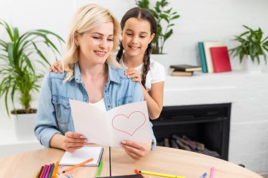 Anne ve kız birlikte ev ödevi yapıyorlar.