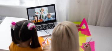 Çevrimiçi uzaktan öğrenme. Bilgisayarlı okul çocukları öğretmen ve sınıf grubuyla görüntülü konuşma yapıyorlar. Çocuk evden ders çalışıyor. Karantina ve koronavirüs salgını sırasında evde eğitim