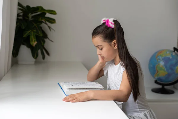 Eğitim ve okul konsepti. Okulda okuyan ve kitap okuyan küçük bir kız öğrenci.. — Stok fotoğraf
