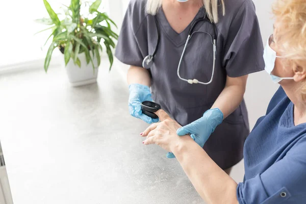 Krankenschwester verwendet Pulsoximeter zur Messung der Sauerstoffsättigung im Blut älterer Patienten — Stockfoto