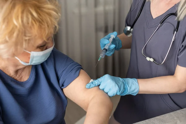 Ανώτερη γυναίκα που λαμβάνει εμβόλιο. Ιατρός που εμβολιάζει ηλικιωμένο ασθενή κατά της γρίπης, της γρίπης, της πνευμονίας ή του κορωναϊού. — Φωτογραφία Αρχείου