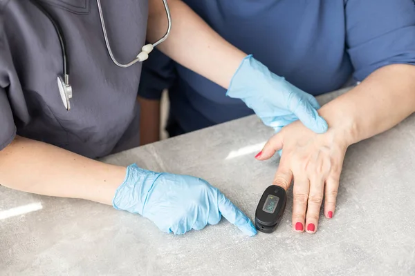 Krankenschwester verwendet Pulsoximeter zur Messung der Sauerstoffsättigung im Blut älterer Patienten — Stockfoto