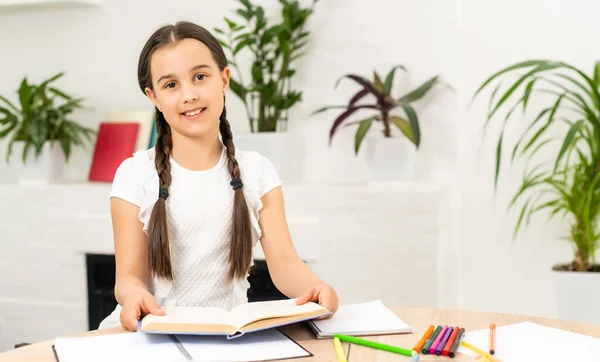 Nahaufnahme Porträt von ihr sie schön attraktiv hübsch kleine fröhliche langhaarige Mädchen am Tisch sitzen Schreibtisch schreiben Artikel Hausaufgaben in hellweißen Klassenzimmer drinnen. — Stockfoto