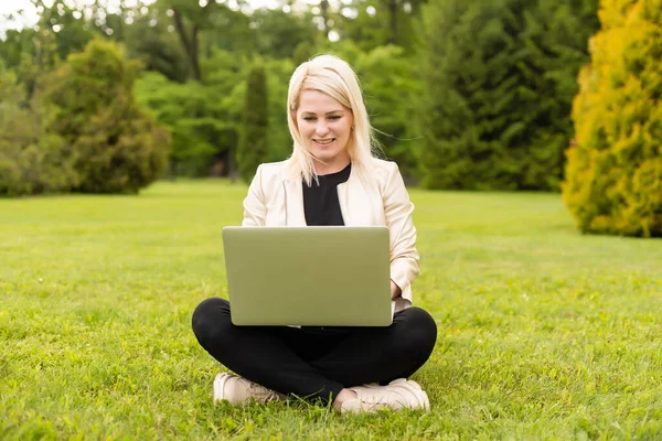 Junge Frau benutzt Laptop im Park — Stockfoto