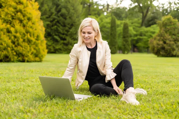 Kobieta copywriter pracuje na laptopie w parku, widok przez ramię — Zdjęcie stockowe