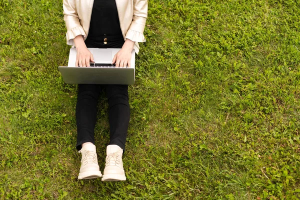 Женщина-копирайтер работает над ноутбуком в парке, смотрит через плечо — стоковое фото