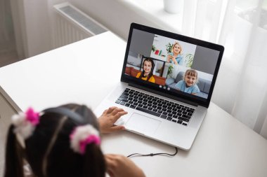 Evde bilgisayarını kullanarak internetten ders çalışan küçük bir kız.