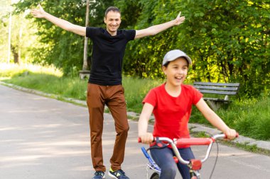 Mutlu baba, kızının bisiklet sürmeyi öğrenmesine seviniyor.