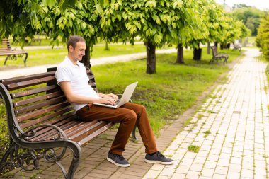 Parkta dizüstü bilgisayarıyla çalışan bir adam.