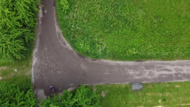 Drone aéreo vista superior voo acima menina passeios de bicicleta na estrada rural — Vídeo de Stock