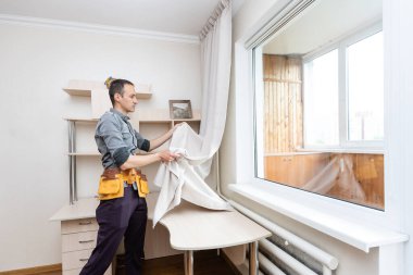 Perdeler, ev onarımı ve yenileme işleri için yeni bir mantar monte eden bir tamirci.
