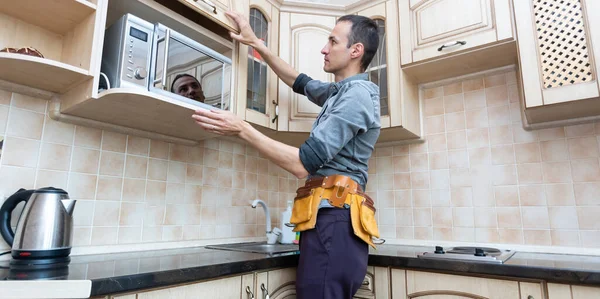 kitchen installation. Worker assembling furniture