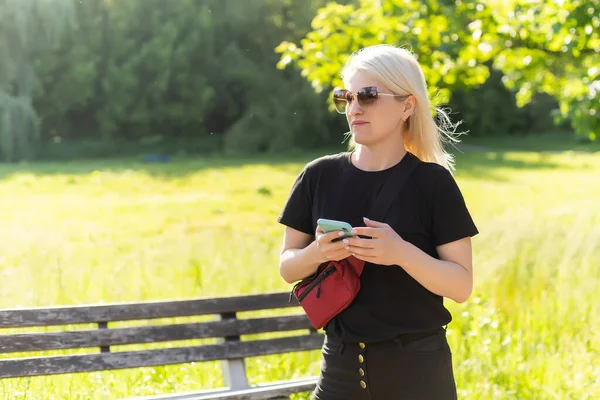 Ung kvinna som använder smartphone i parken. — Stockfoto