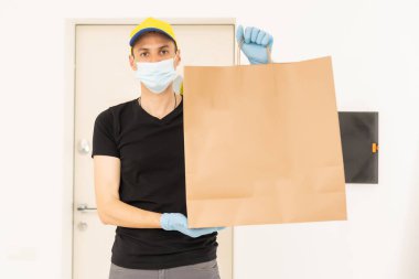 Karton kutuları tıbbi lastik eldiven ve maskeyle taşıyan teslimatçı. kopyalama alanı. Hızlı ve ücretsiz teslimat. İnternetten alışveriş ve ekspres teslimat. Karantina