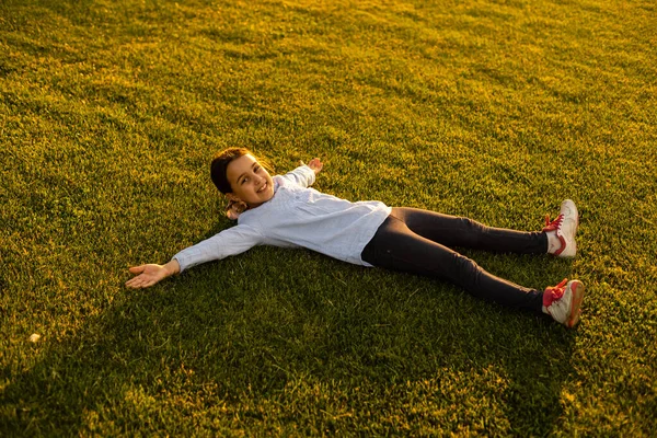 Kaukasisches kleines Mädchen im Park in den Strahlen der untergehenden Sonne — Stockfoto