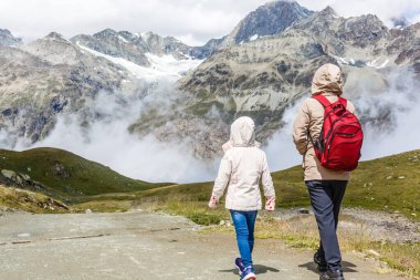 Sırt çantalı anne ve kızı gün içinde dağların yamacında oturuyorlardı..