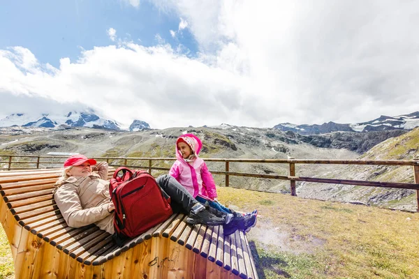 Мать и дочь с рюкзаком сидят на тропинке в горах в дневное время. — стоковое фото