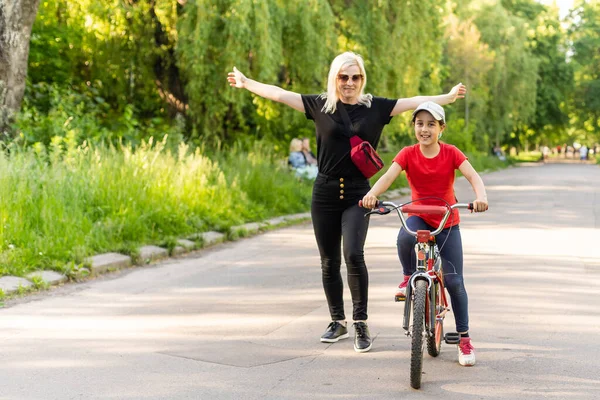 フロントビューポートレートのcaucasian母見ます彼女の眼鏡を通して彼女の娘を助けながら自転車に乗る — ストック写真