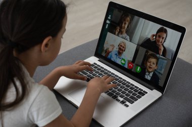 Mesafe öğrenme. Kulaklıklı neşeli küçük kız bilgisayarını kullanarak internetten e-öğrenim sistemini inceliyor..