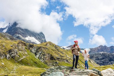 Sırt çantalı anne ve kızı gün içinde dağların yamacında oturuyorlardı..